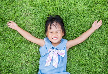 Asian little girl smile and lay on grassの写真素材