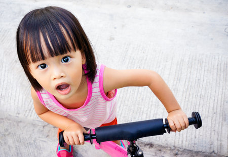 little asian girl question face acting on bicycleの写真素材