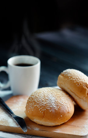 Tasty buns with hot coffee on cutting boardの写真素材