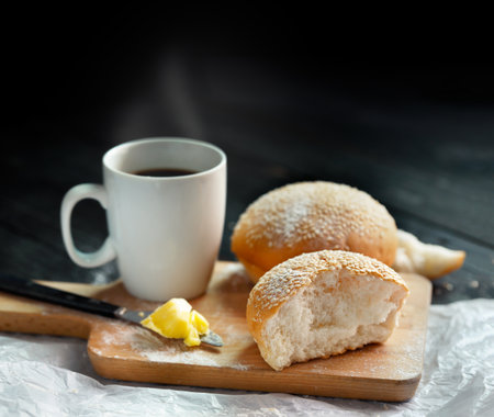 Tasty buns with hot coffee on cutting board