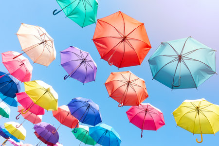 colorful umbrellas float on to bright blue sky background