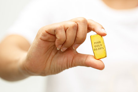 Woman hand holding a gold bar to take a close up photoの写真素材