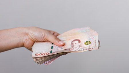 Hand hold Thai baht banknotes, isolated backgroundの写真素材