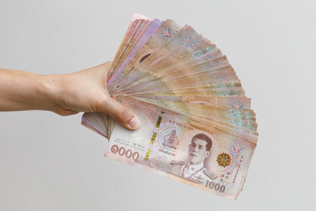 Hand hold Thai baht banknotes, isolated background