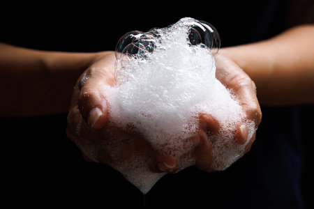 Detergent bubbles in the palm of hand. isolated black background.の写真素材