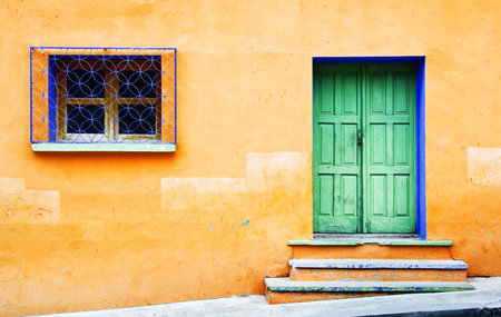 A colorful door and window on a hillside home.の写真素材