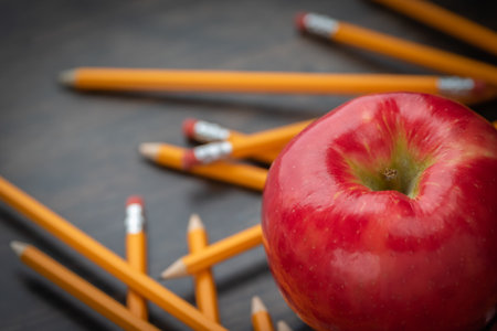 red apple with yellow pencils on a deskの写真素材