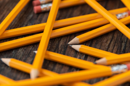 yellow school pencils scattered laying on a wood surface with tips togetherの写真素材