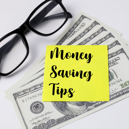 Top view of a glasses and money with text Money saving tips written on yellow sticky notes