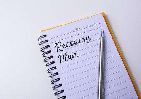 Top view of a pen and notebook with text written Recovery plan. Education and business conceptの写真素材