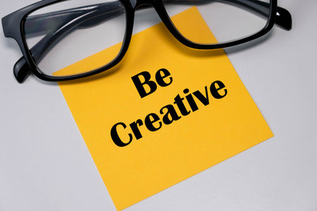Be creative text written on a sticky note with eye glassesの写真素材