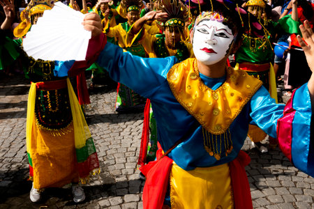 Asian dancer in white mask and folk lore dress moving along the street in the city carnival