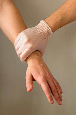 A hadn with a protection glove carefully grip an armの写真素材