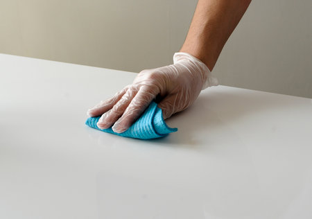 A hand with a protection glove on mopping the tableの写真素材