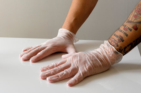 Two hands with protection gloves lean at a tableの写真素材