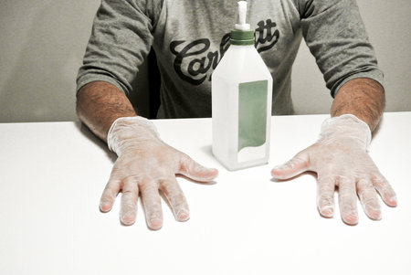 man with protection gloves and a bottle of desinfection for the handsの写真素材