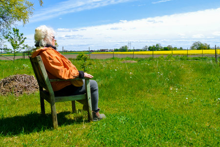 A lonely lady sitting in her garden and looking out and the landscapeの写真素材