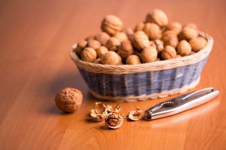 Nuts in a basket with the nutcracker, on a wooden background の写真素材