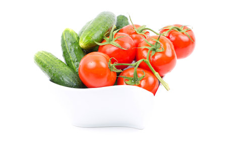 Fresh cucumbers and tomatoes in a porcelain bowlの写真素材