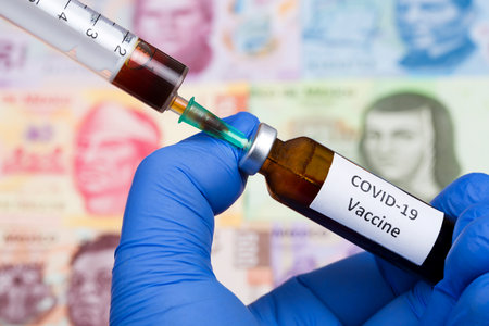 Vaccine against Covid-19 on the background of Mexican moneyの写真素材