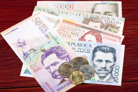 Colombian Pesos coins and banknotes on a wooden backgroundの写真素材