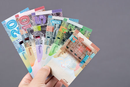 Kuwaiti money - dinar in the hand on a gray background