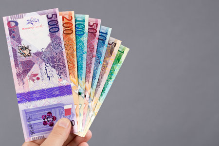 Qatari money - riyal in the hand on a gray background