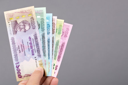Bangladeshi money - Taka in the hand on a gray backgroundの写真素材