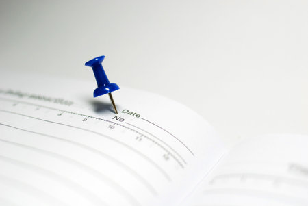 Isolated blue push pin on white notebookの写真素材