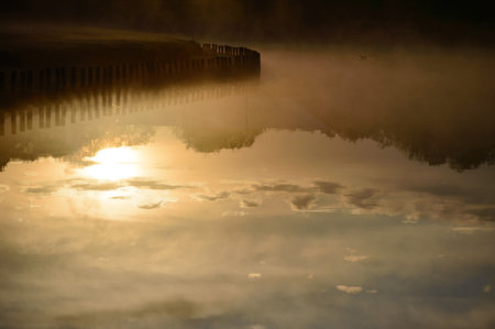 Morning sky and sun with water reflection mist rising from the lake
