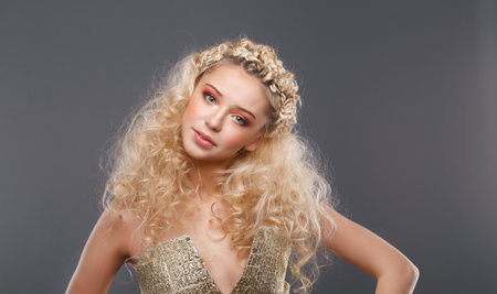 Beautiful young girl with blond curly hair looking at cameraの写真素材