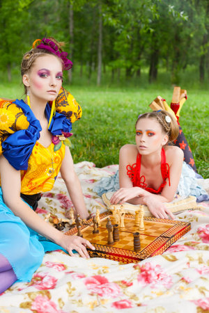 Portrait of two young beautiful women playing chess. outdoorsの写真素材