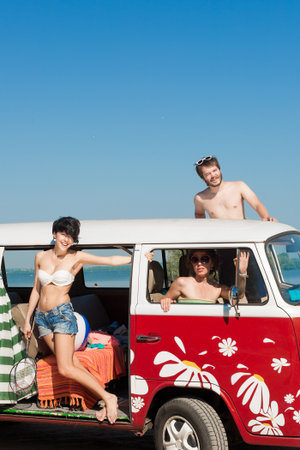 young people enjoying the sun in car with blue cloudy sky and sun in background - outdoors
