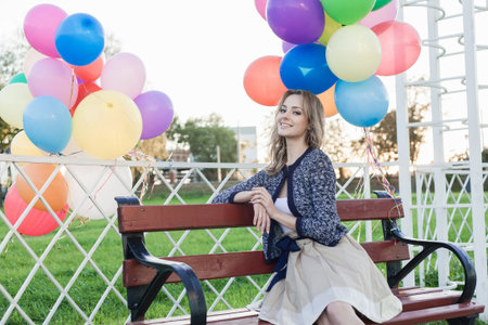 Portrait of a happy woman sitting in a park against the sunset, outdoorsの写真素材