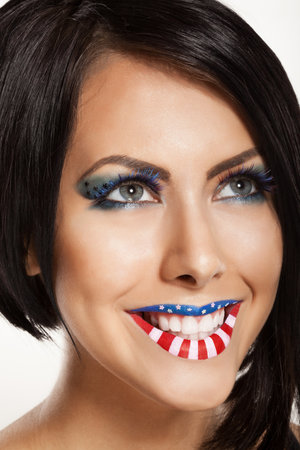 Woman beautiful face with perfect makeup. on the lips and eyes painted an American flagの写真素材