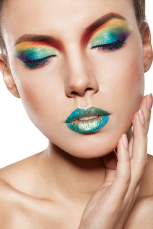 beautiful female face with rainbow makeup. girl witn closed eyes touch her face by handの写真素材