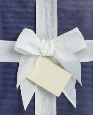 Blue gift box with white ribbon and beige noteの写真素材