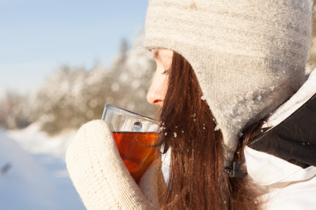 girl attractive drinking tea over winter nature background outdoorの写真素材