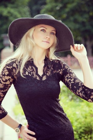 Portrait of pretty cheerful woman wearing black dress and straw hat in sunny warm weather day  Walking at summer park  Outdoorsの写真素材