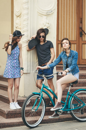 Two young women and man standing on the stairs of house=の写真素材