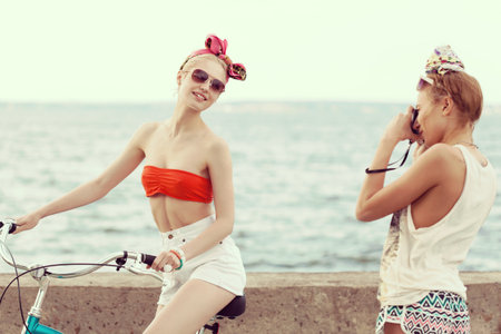Beautiful young woman taking a picture with an old camera against a sea. Outdoor, lifestyleの写真素材