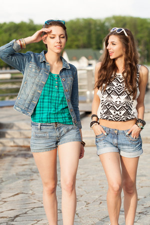 Two young woman walking and talking near the river. Outdoors, lifestyleの写真素材