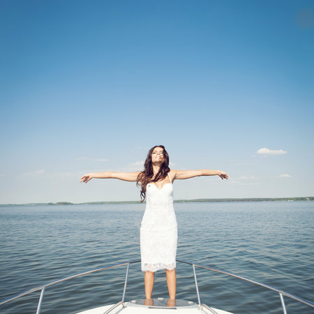 Young happy beautiful woman enjoying on the luxury boat in open sea in summer. Caucasian female model. Outdoors, lifestyle.の写真素材