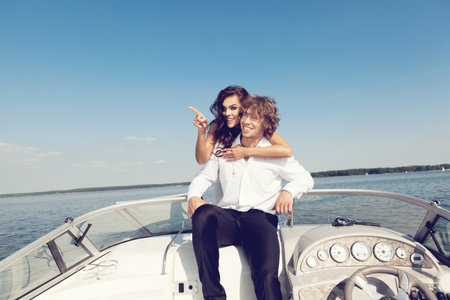 Sexy lovely couple on the luxury boat in open sea in summer. Young man and sensual brunette outdoor portrait in classic dress. Outdoors, lifestyle.の写真素材