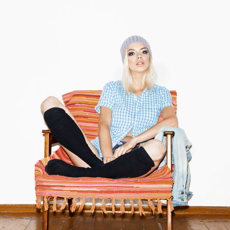 Beautiful young woman in a black socks and blue shirt sitting in armchair. Indoorsの写真素材