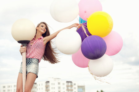 Happy young girl with big colorful latex balloons. Beauty Romantic Girl Outdoors. Woma  with long hair  having fun.の写真素材