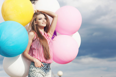Happy young woman  with big colorful latex balloons. Outdoors, lifestyleの写真素材