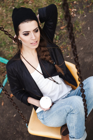 Portrait of a beautiful girl hipster on a swing. Outdoors.の写真素材