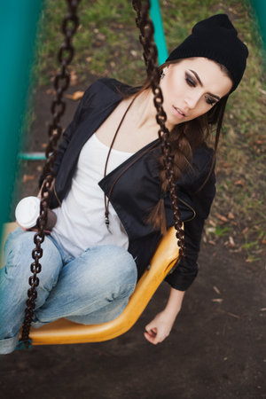 Portrait of a beautiful girl hipster on a swing. Outdoors.の写真素材