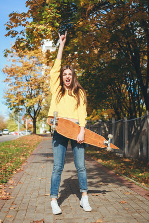 Beautiful young woman  having fun with a longboard in the afternoon. Skateboarding. Outdoors, lifestyleの写真素材